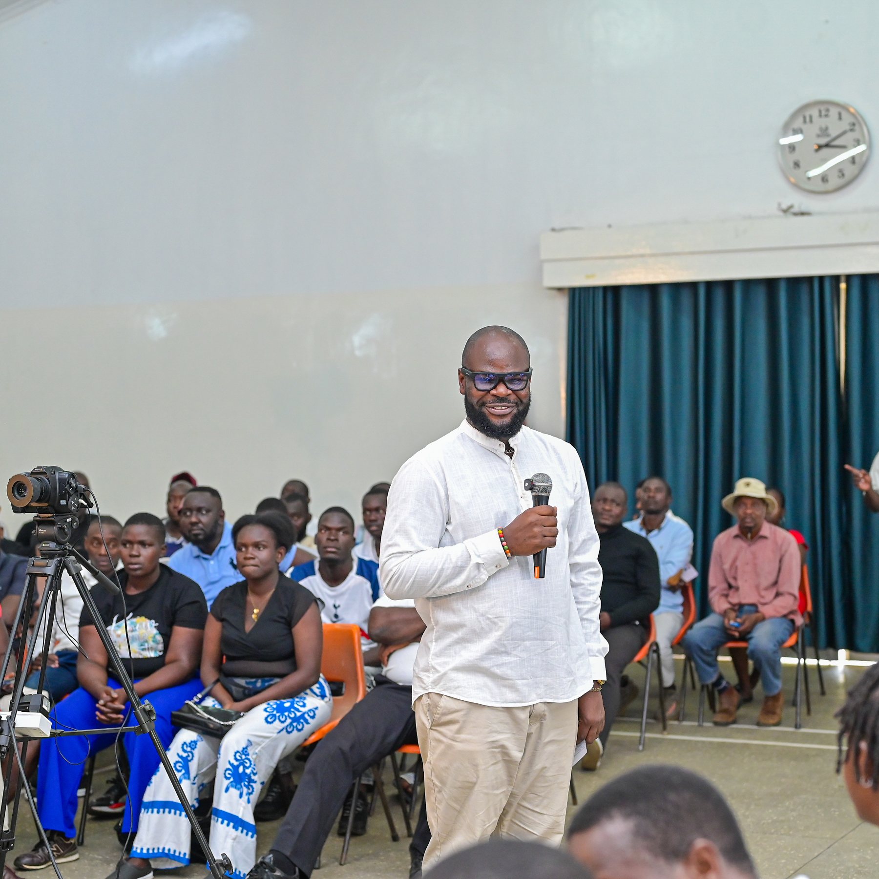 A man speaking into a microphone among the town hall audience