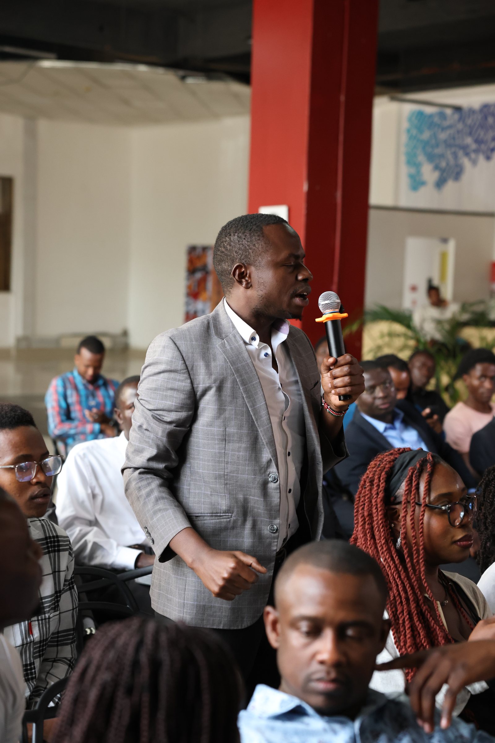 An audience member in a grey suit speaking during the Nairobi forum