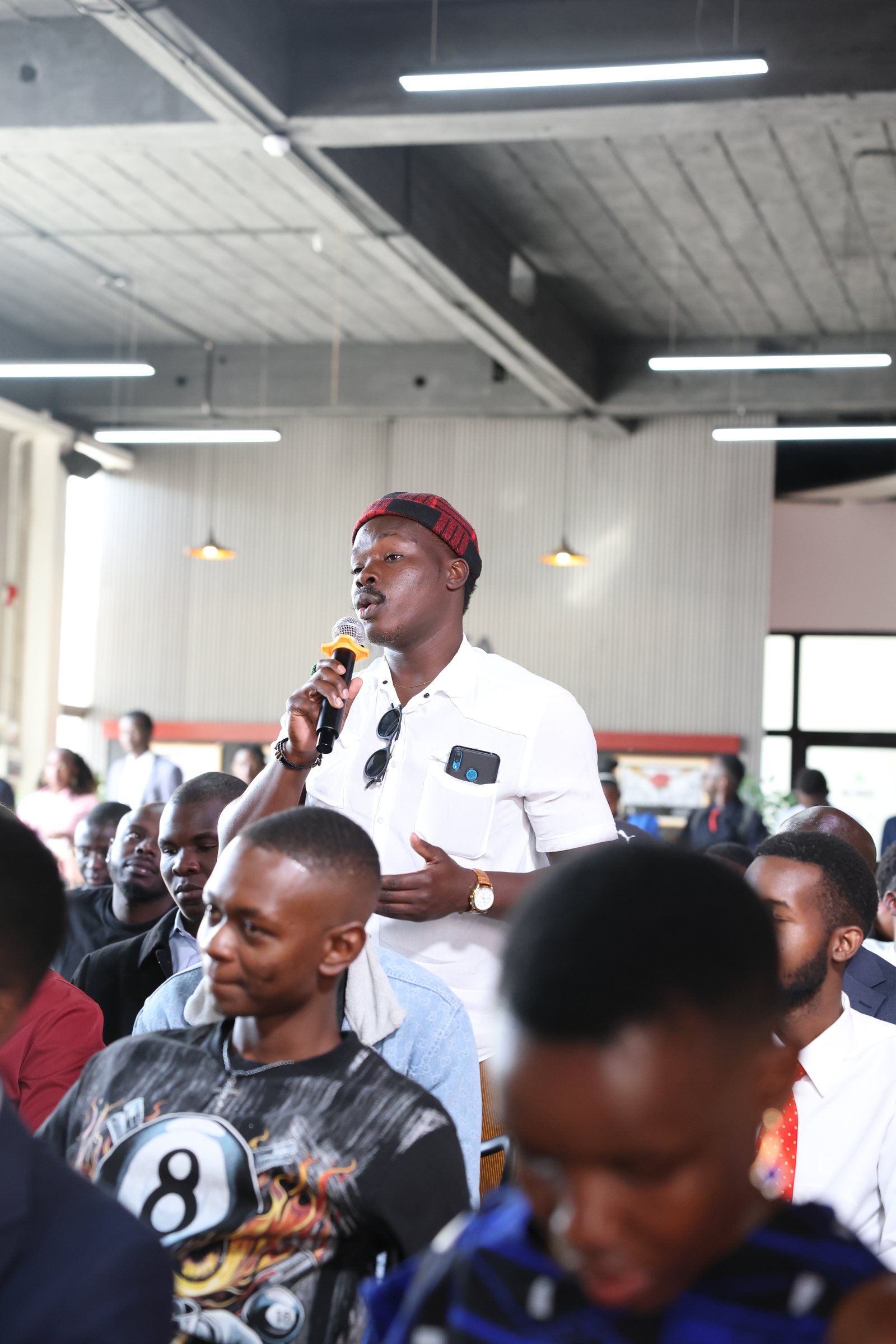 A man in a white shirt making a contribution among seated attendees