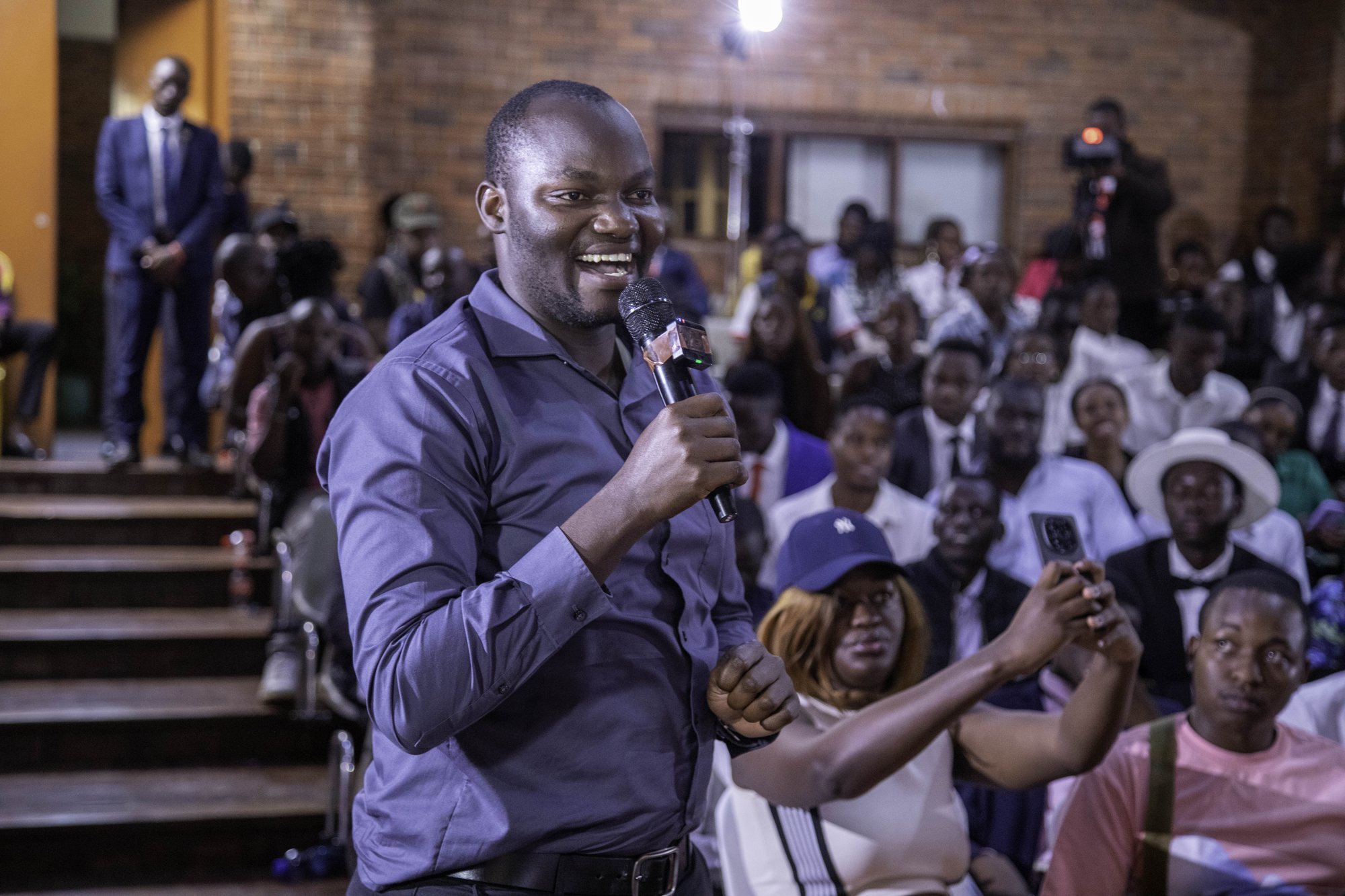 A man speaking among a full Nairobi town hall audience