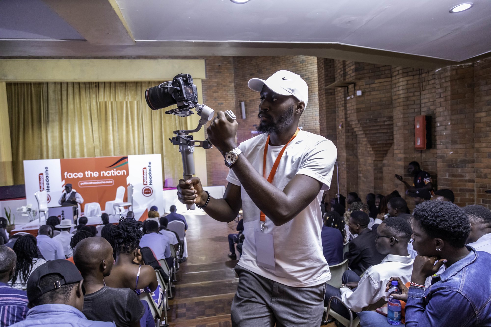A camera operator filming the forum with the audience beyond