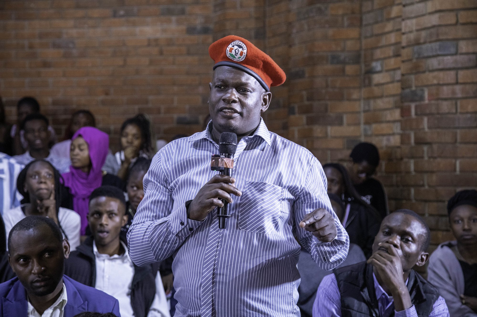 A man in a red beret speaking from the audience