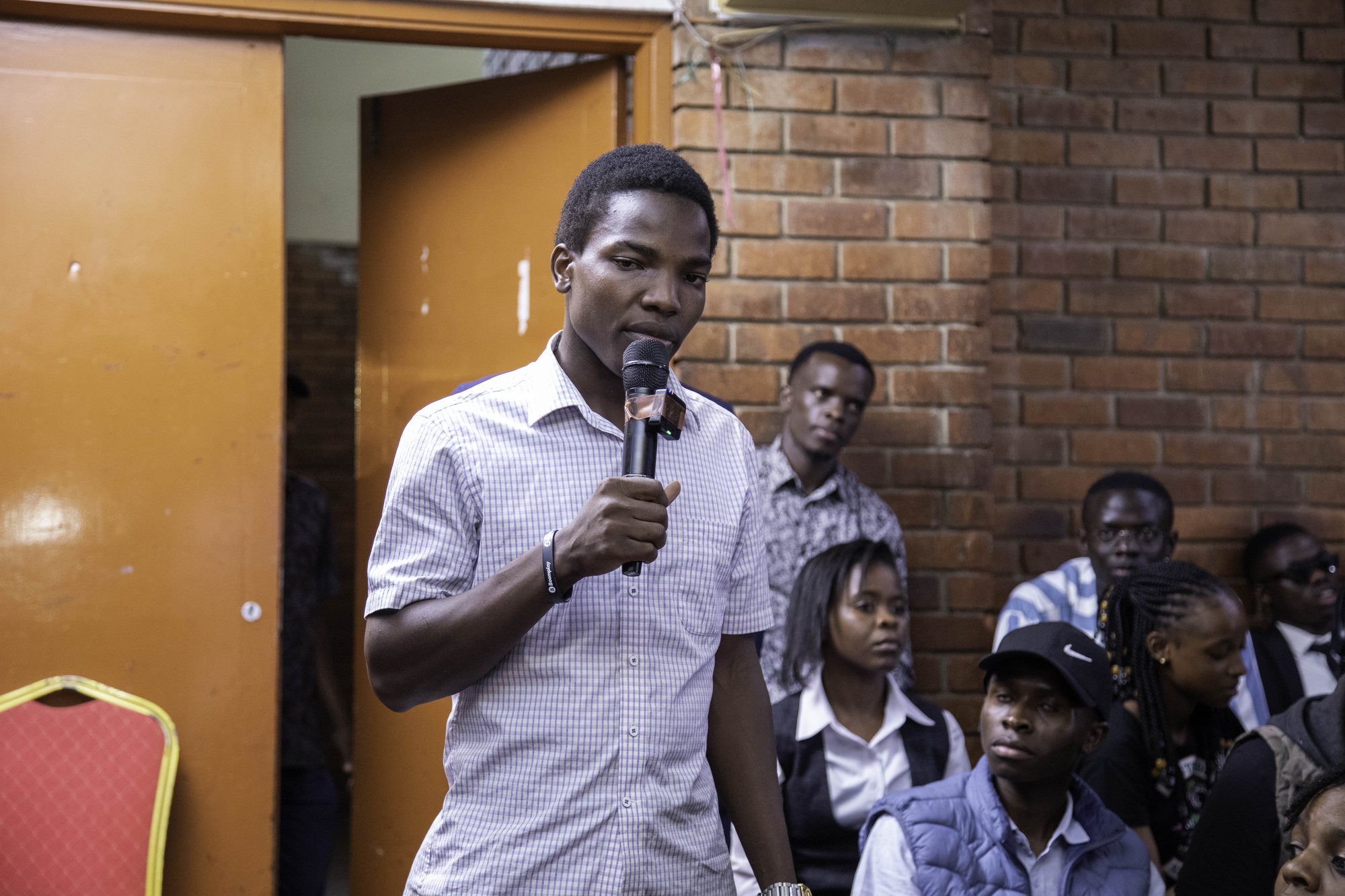 A young man speaking into a microphone in the audience